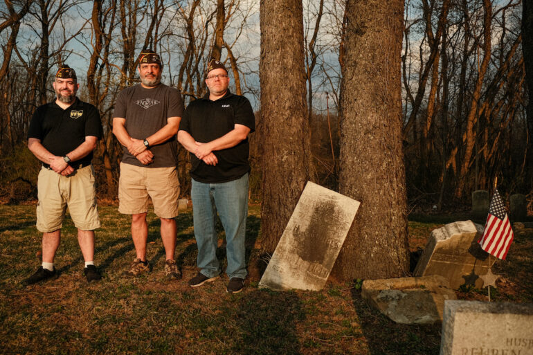 Image of three men standing next to old grave stones