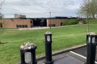 Image of the May 4 memorial, four posts in a parking space, in front of the Gym Annex