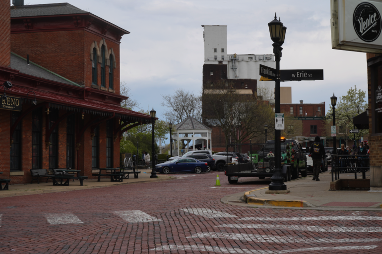 Photo of a red brick road intersection in downtown Kent. The street signs on the corner read franklin ave and Erie Street