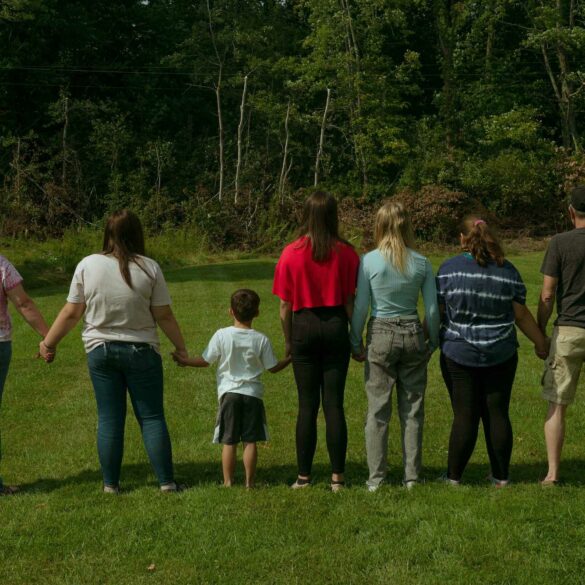 Image of a foster family in a grassy yard, with their backs to the camera for privacy