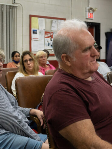Image of residents seated in a local fire station watching a meeting