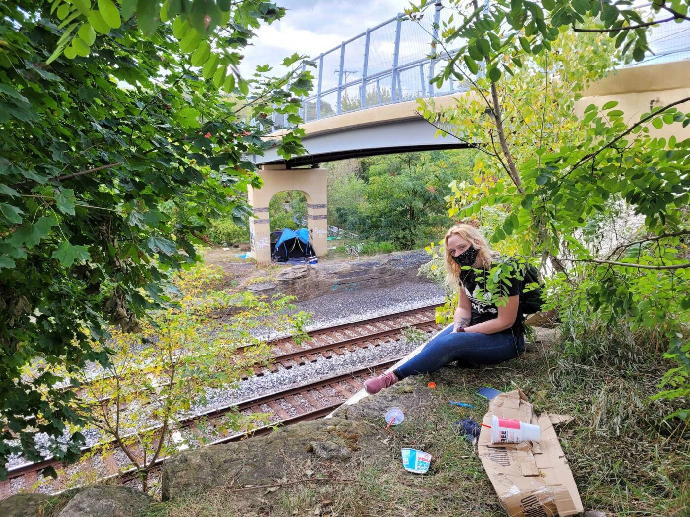 Image of a woman in jeans and a T-shirt near the railroad tracks in Kent under the Haymaker bridge