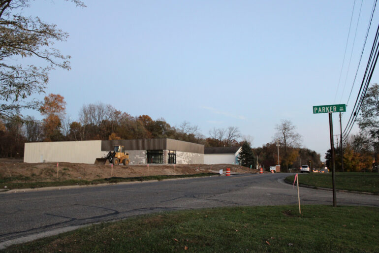 image of a gray block building on the side of a main road in the fall