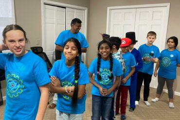 Image of several smiling boys and girls dressed in identical blue shirts