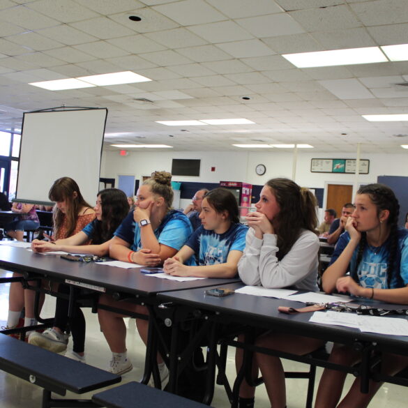Image of several young women seated at a high school cafeteria table during a board meeting
