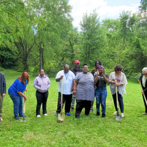 Image of a family and public officials with shovels about to dig into a vacant grassy lawn